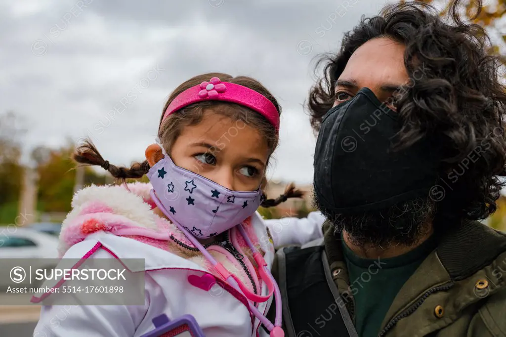 father and daughter with protective face masks and halloween costume