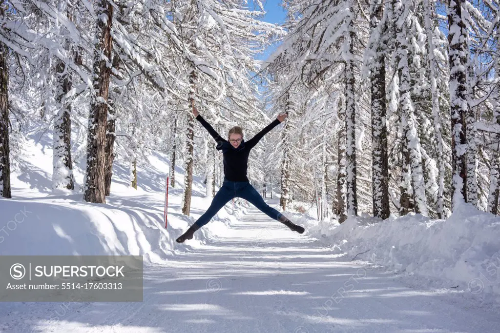 Happy young women jumping on the snow road