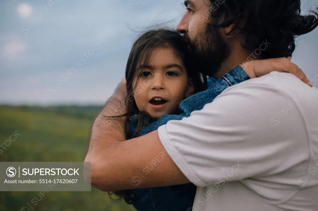 dad kissing daughter while carrying her on hike