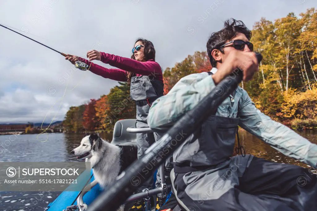 Man and woman anglers with dog in a boat during foliage season