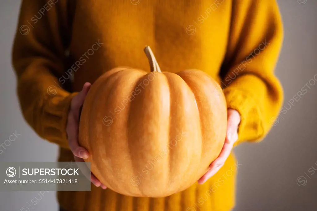 woman holding fresh pumpkin while standing in white background