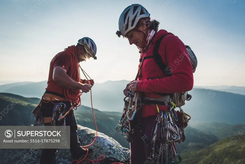 Man & woman sort rock climbing gear during early morning in mountains