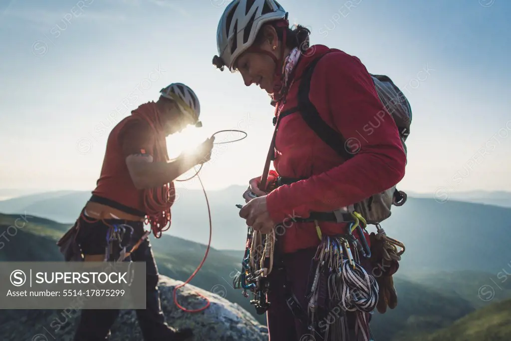 Man & woman sort rock climbing gear during early morning in mountains