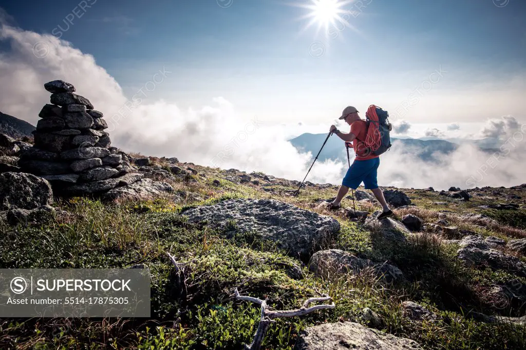 Man hiking through mountains with backpack and hiking poles