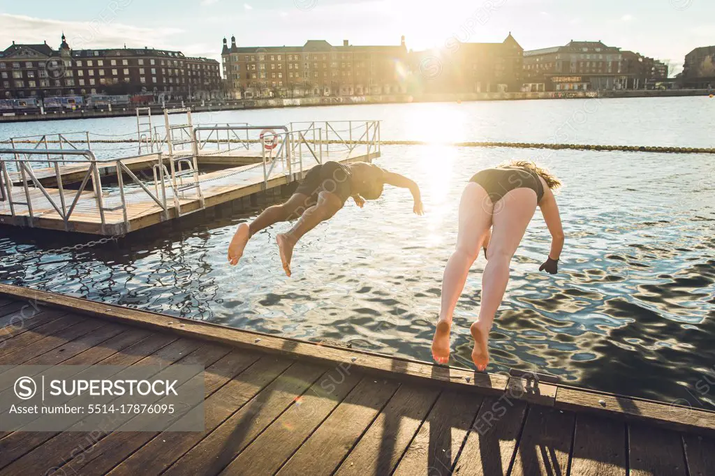 Two Friends of Different Age and Race Jumping in Cold Water in Denmark