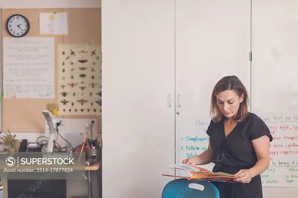 Elementary School teacher reading a book in her classroom.