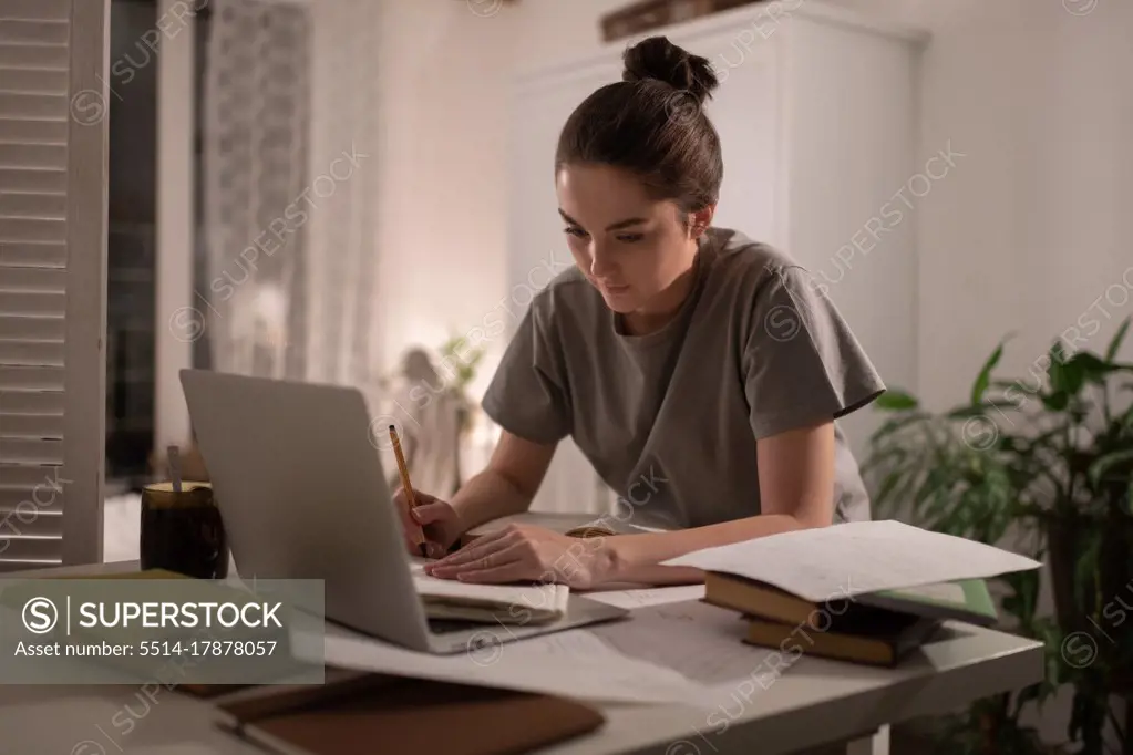 Student taking notes in notebook during studies at home