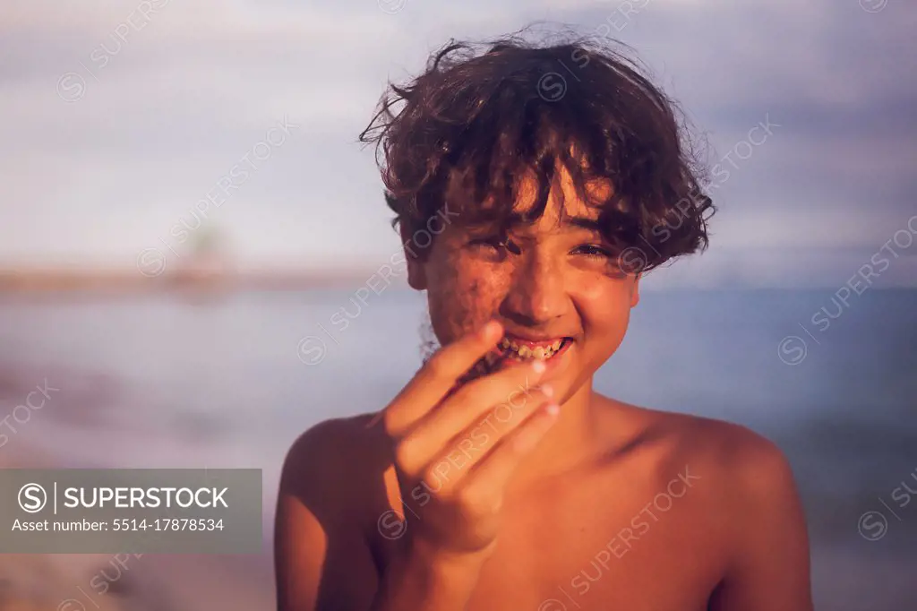 Smiling pre teen boy holding a coral on a tropical beach.