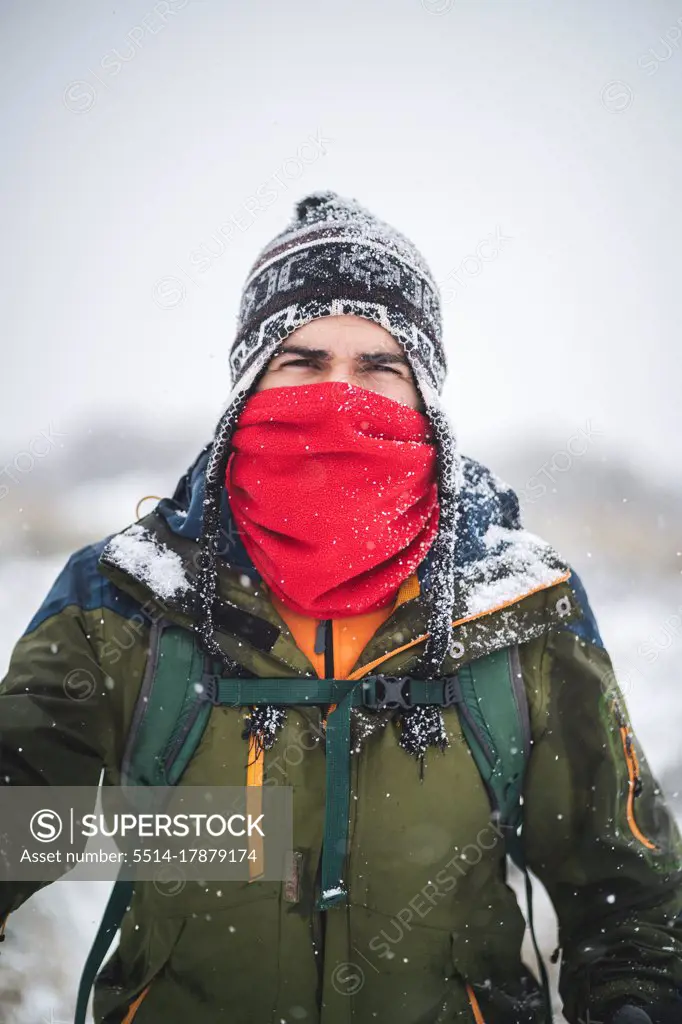 A man with face covered treks under heavy snow