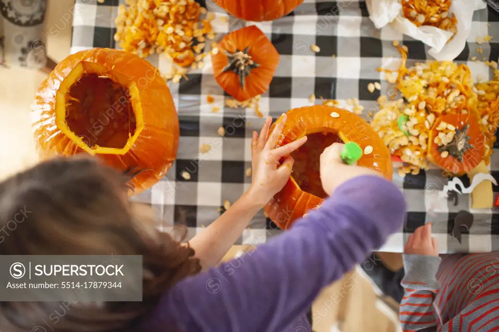 Above head view of kids scooping out pumpkin seeds at table