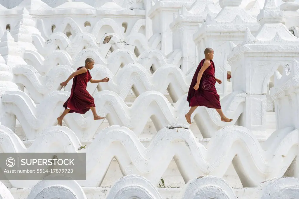 Two novice monks running and jumping at Hsinbyume pagoda, Mingun, Mandalay, Sagaing Township, Sagaing District, Sagaing Region, Myanmar