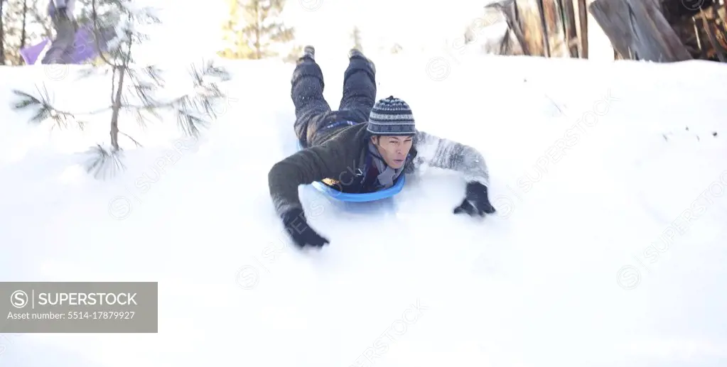 Man sliding down snowy hill in sled