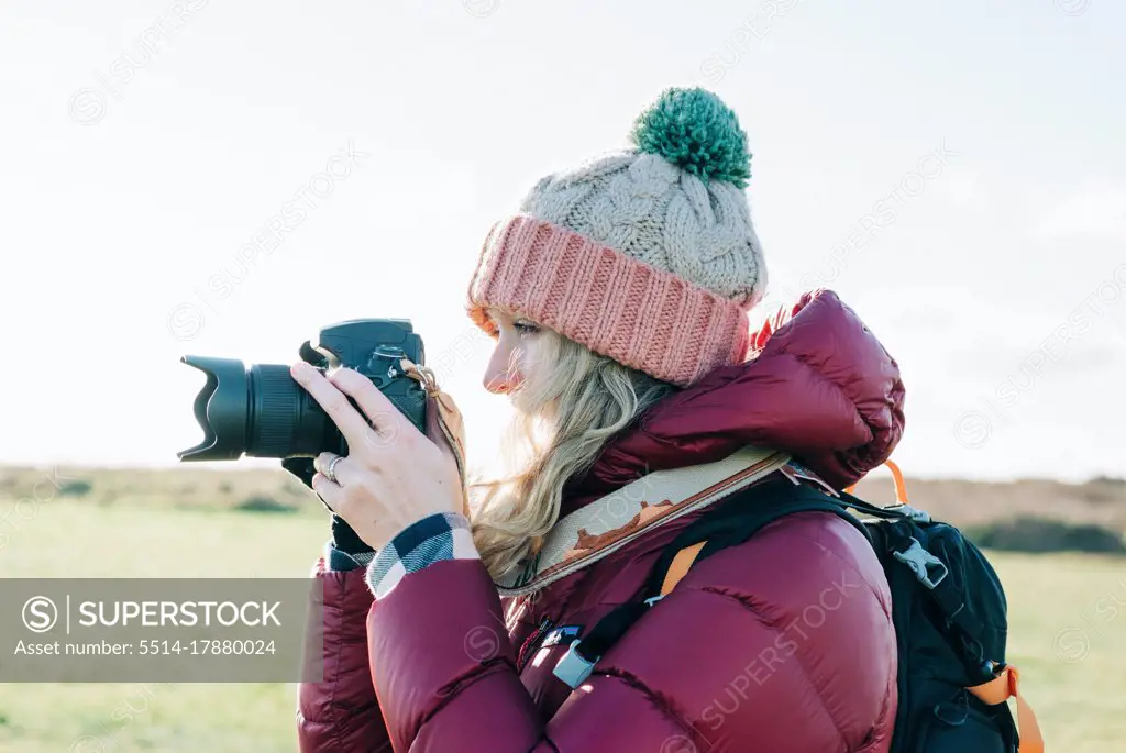 woman holding a DSLR ready to take a shot whilst at the sunny beach