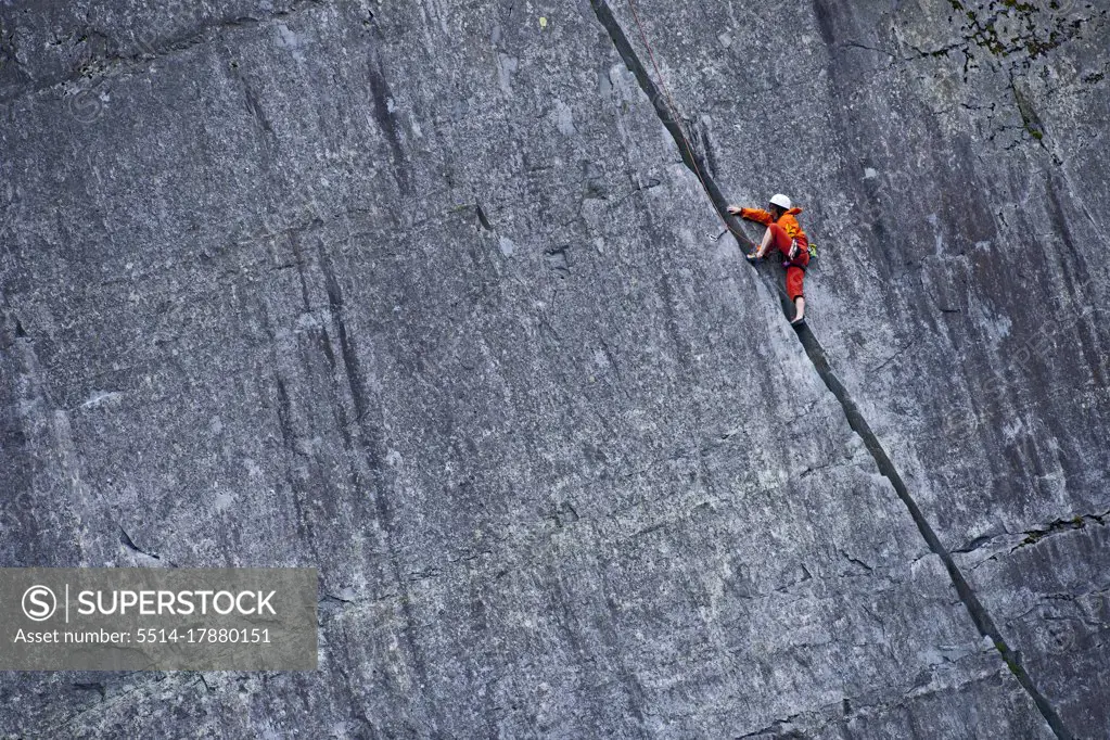 woman climbing up steep rock face at Slate quarry in North Wales