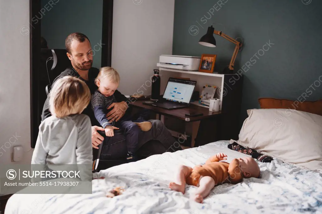 Kids on top of dad who is trying to work while from home during covid