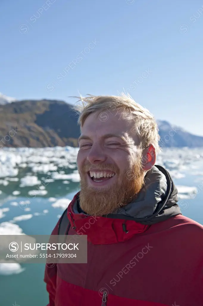 blonde man with beard laughing ot fjord in south Greenland