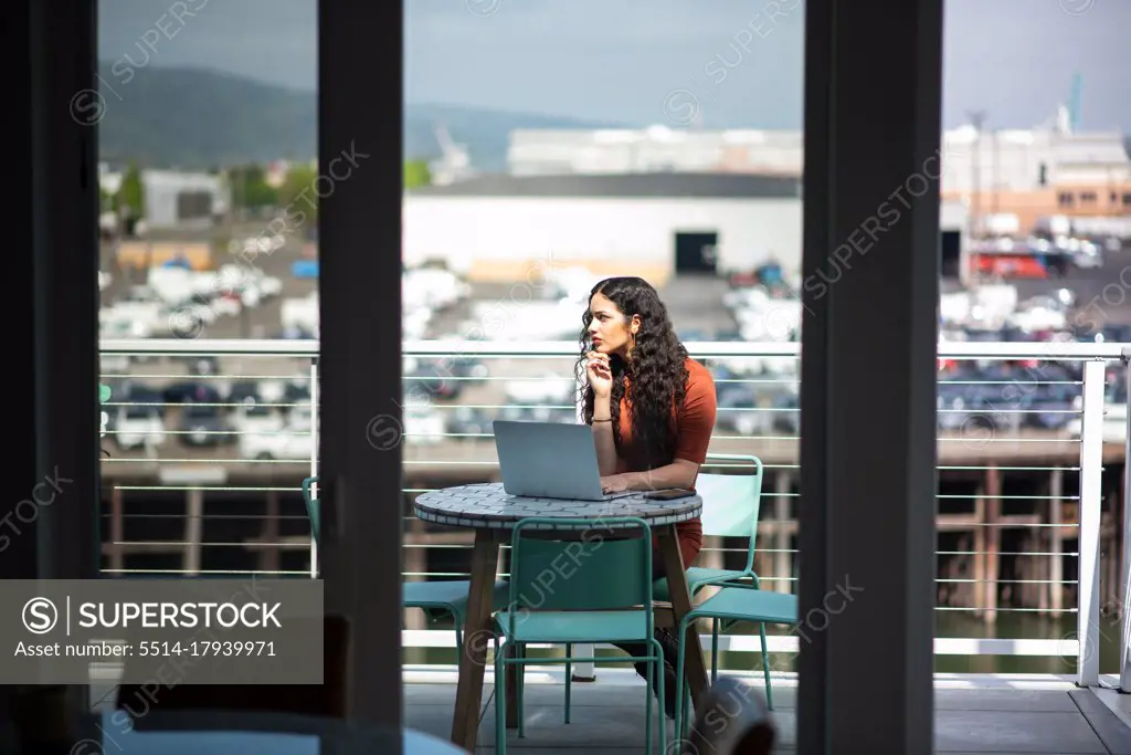 Woman with laptop working at table on patio