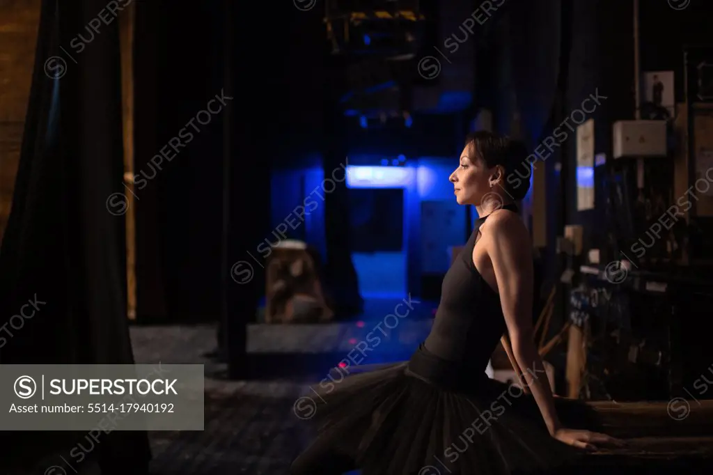 Adult ballerina sitting behind stage