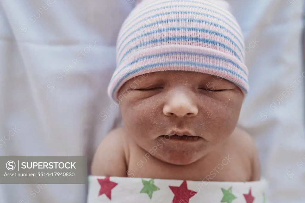 High angled close up view of swaddled newborn in hat at hospital