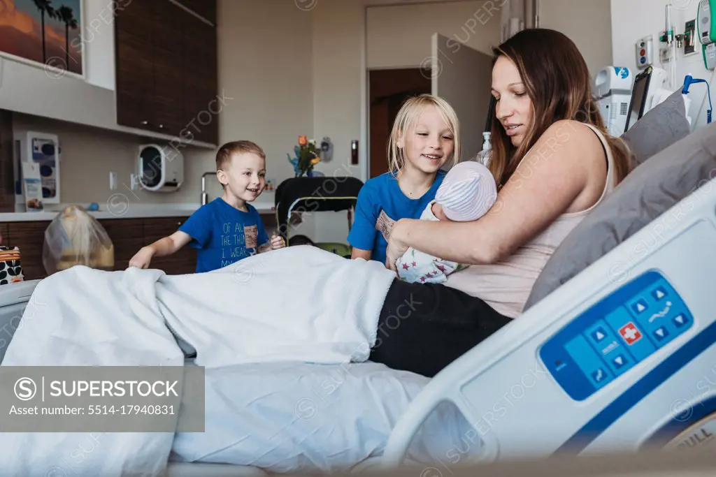 Young brothers meeting newborn baby for the first time in hospital