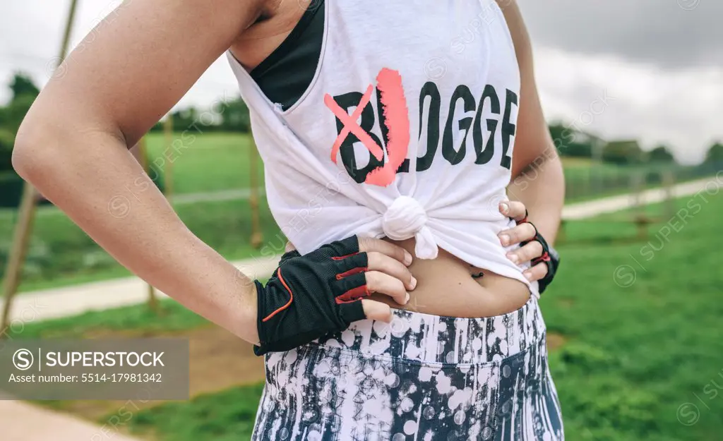 Female athlete with knotted shirt posing