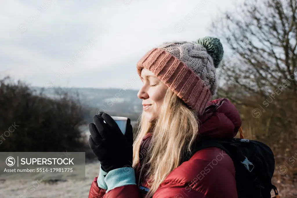 woman smiling holding a hot drink whilst enjoying the cold air in UK