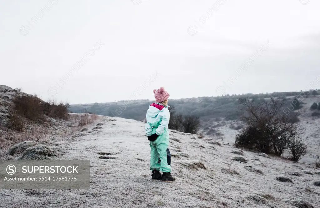 young girl stood on the top of a hill in the English countryside