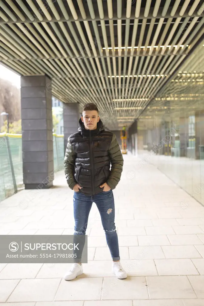 Young man standing hands on pocket on a corridor while looking camera