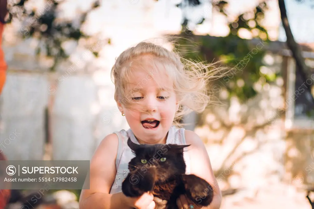 happy little girl playing with kitten