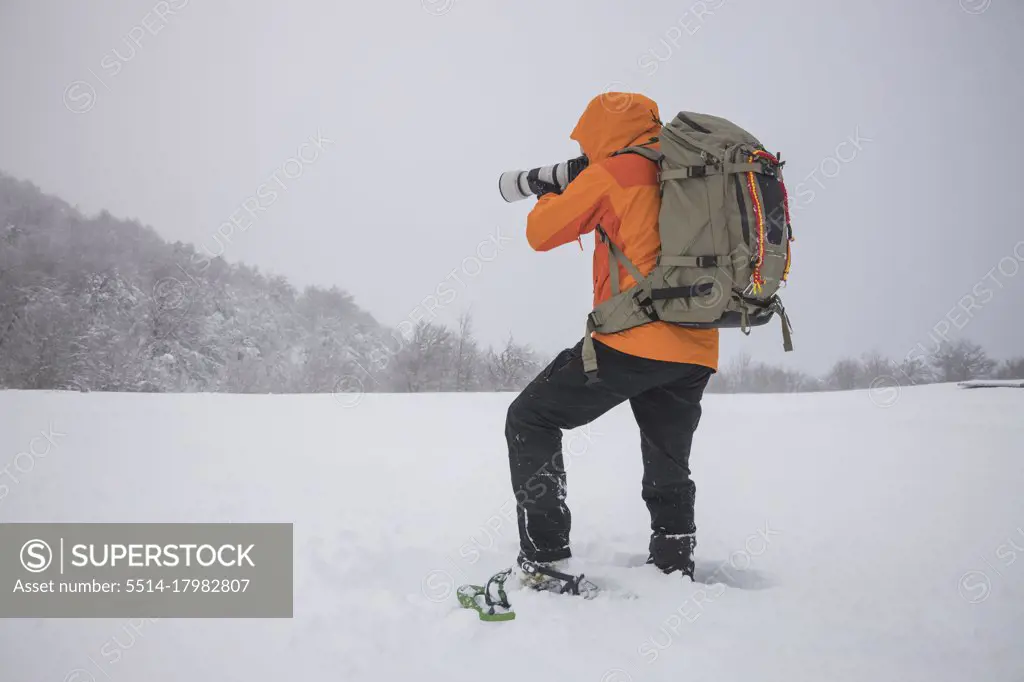 photographer working with snowshoes in covered field