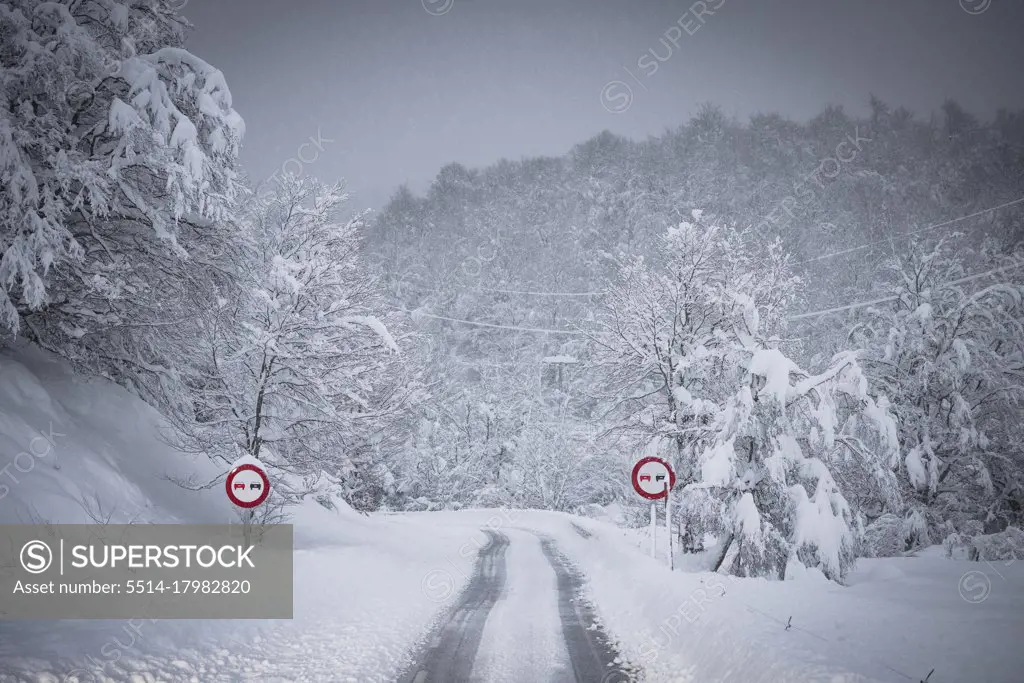 high mountain road and traffic signs in the middle of a snowfall