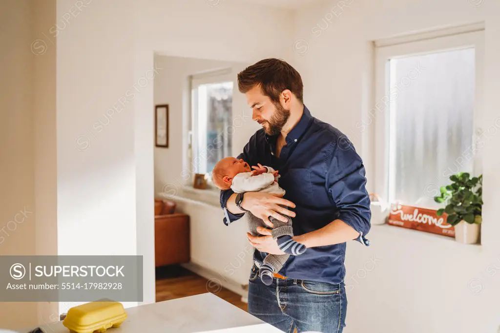 Happy dad holding his newborn baby at home during quarantine