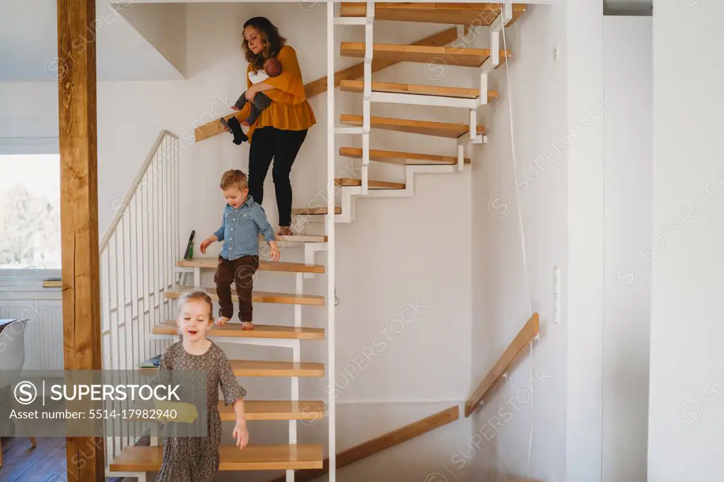 Mom and children walking down the stairs at home during quarantine