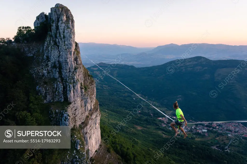 Slackliner sitting in the void waiting to walk the line