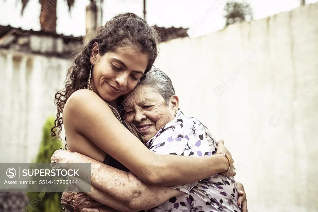 Mexican women smile in loving hug embrace on summer street Mecxico