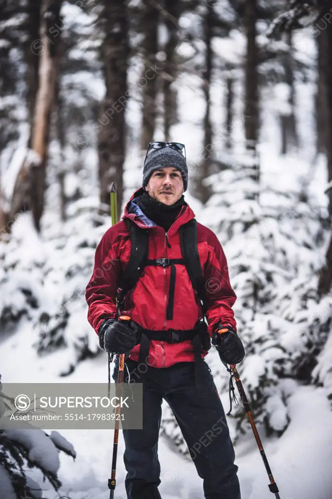 portrait of male skier with red jacket in snow covered woods in Maine