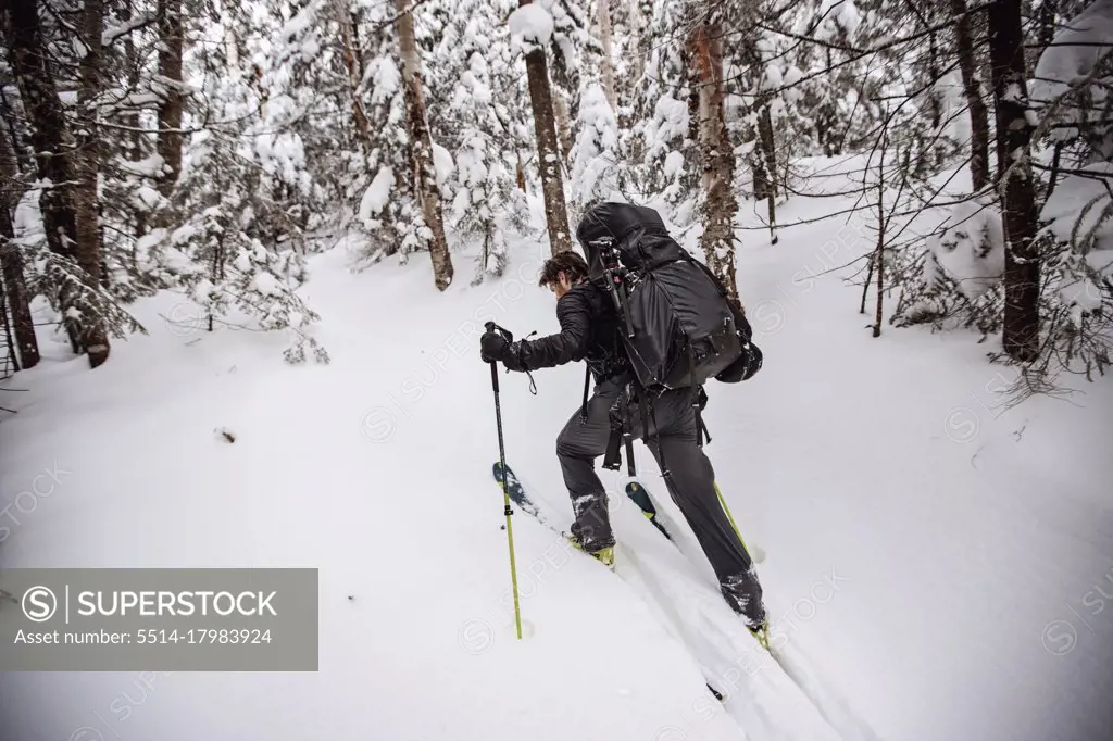 Make skier struggles with heavy pack skinning uphill in snow,