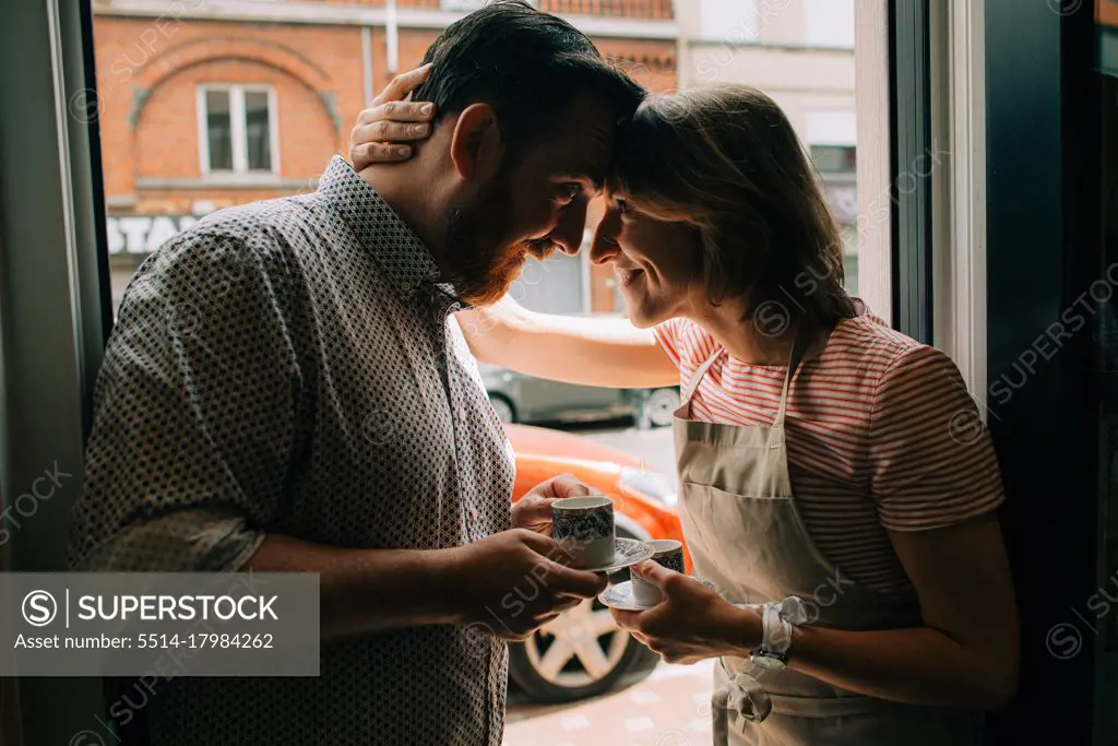 Young couple in love drinking coffee, smiling while standing at door