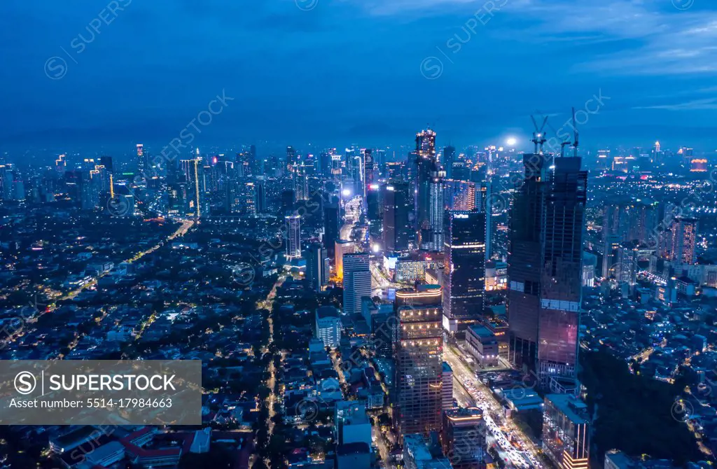 Aerial wide panoramic view of modern cityscape with high rises in the night Skyscrapers and residential neighborhoods in blue night light in Jakarta, Indonesia