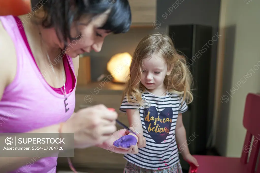 Mother painting on daughter's palms with watercolours