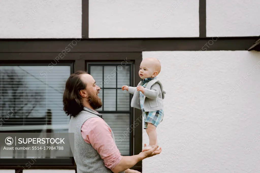 Fun dad playing with baby son in front yard in spring