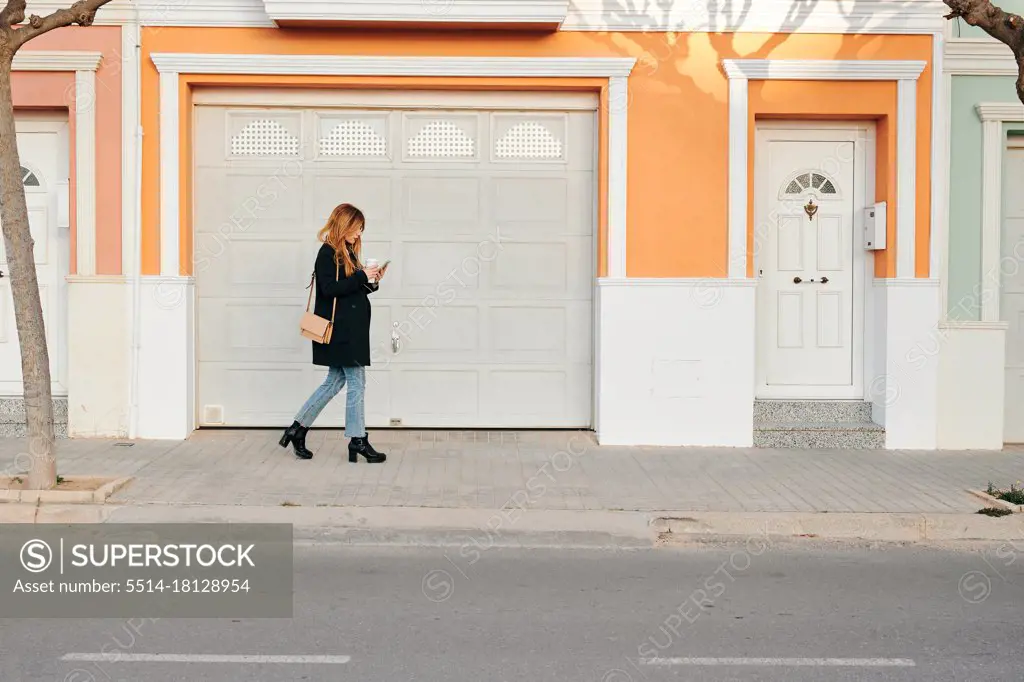 Woman walks while she is looking at her smartphone on the street