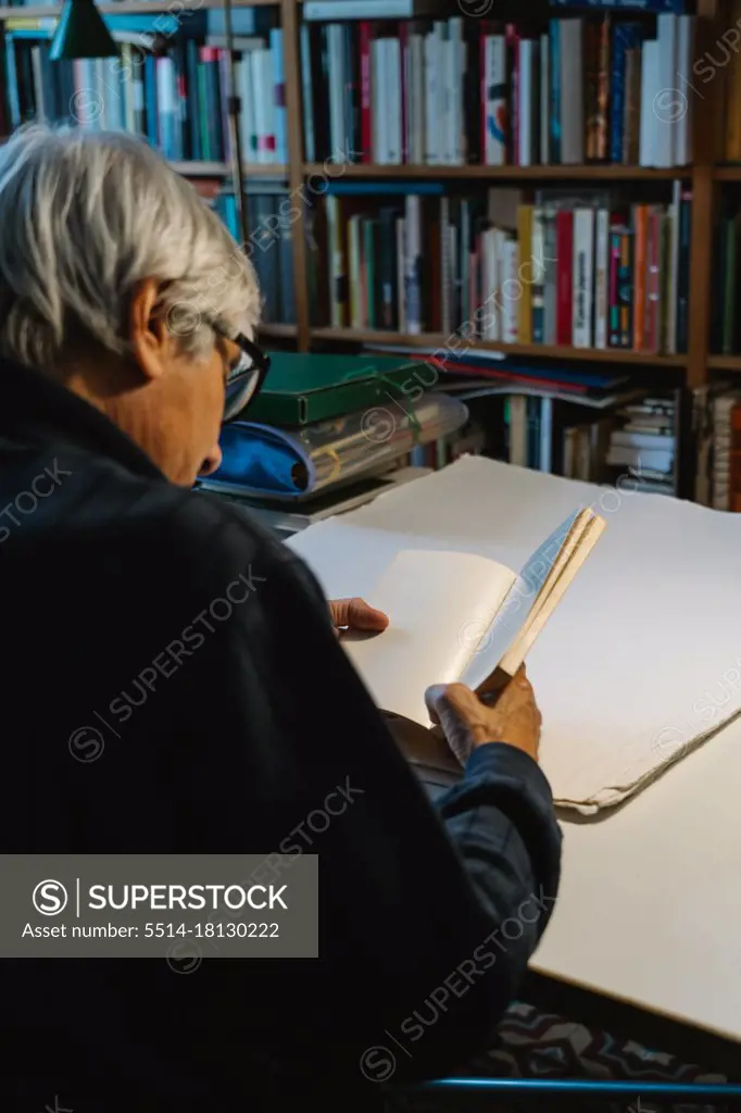 old man reading a book in his home library