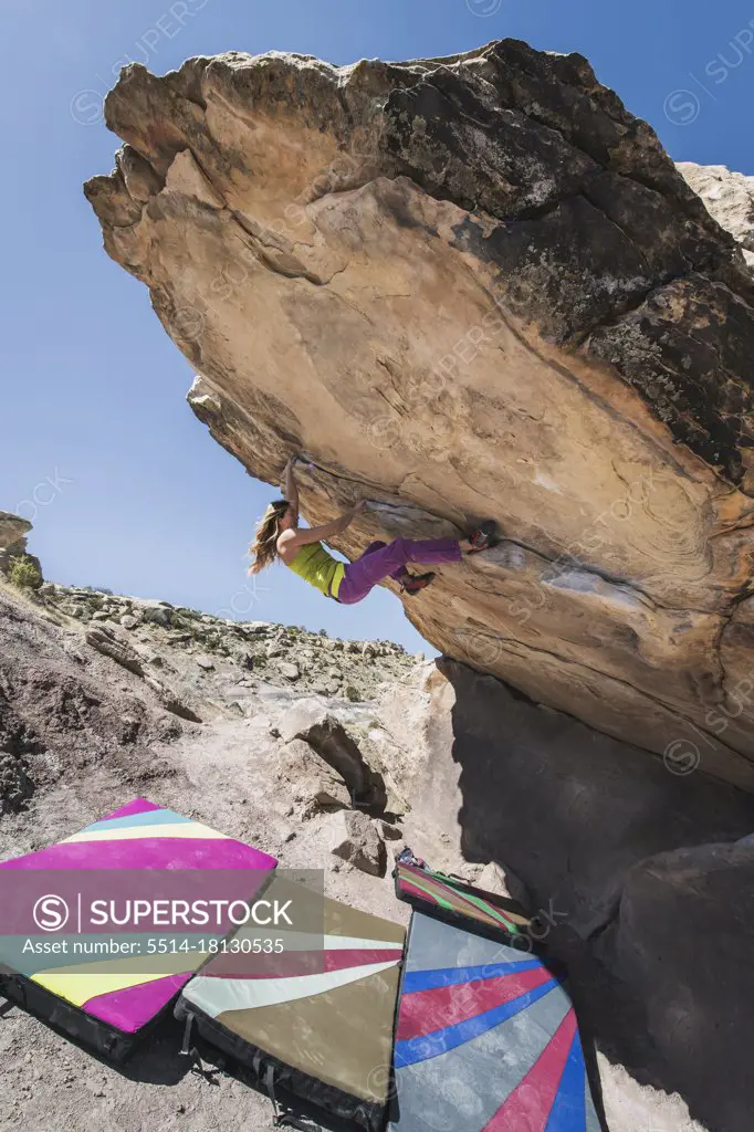 Woman practicing bouldering on rock during sunny day