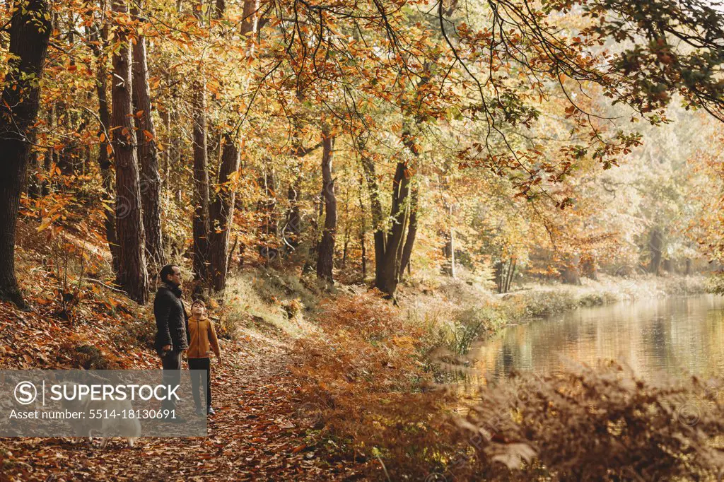 Boy and father standing under trees next to canal in fall