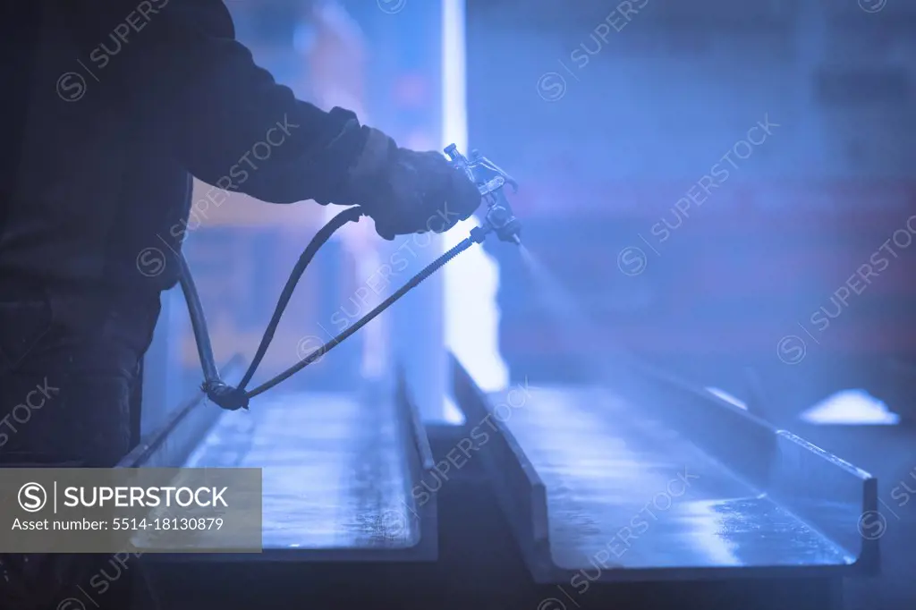 Man with gloves  painting and lacquering steel with compressor