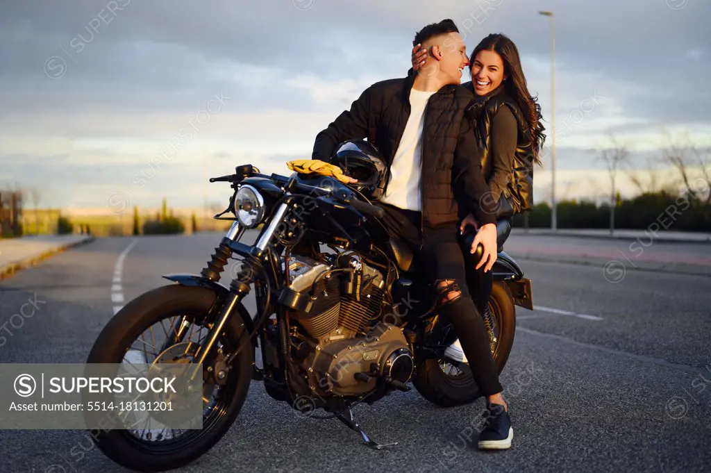 Portrait of happy young couple on scooter enjoying road trip