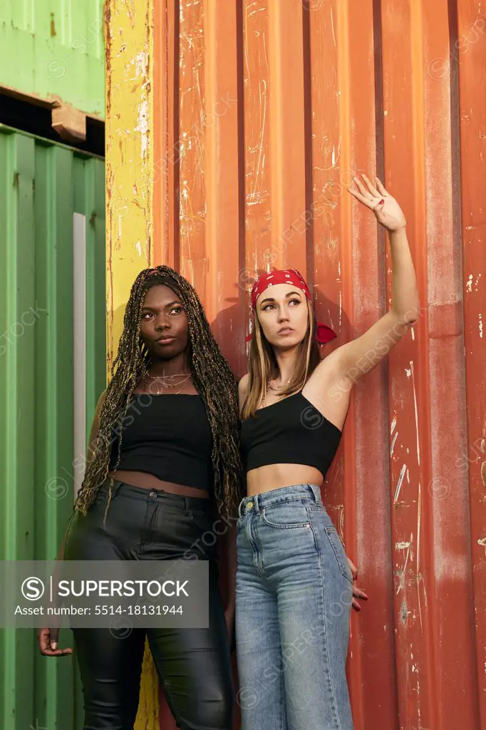 Two multi-ethnic young women in urban clothing pose at sunset