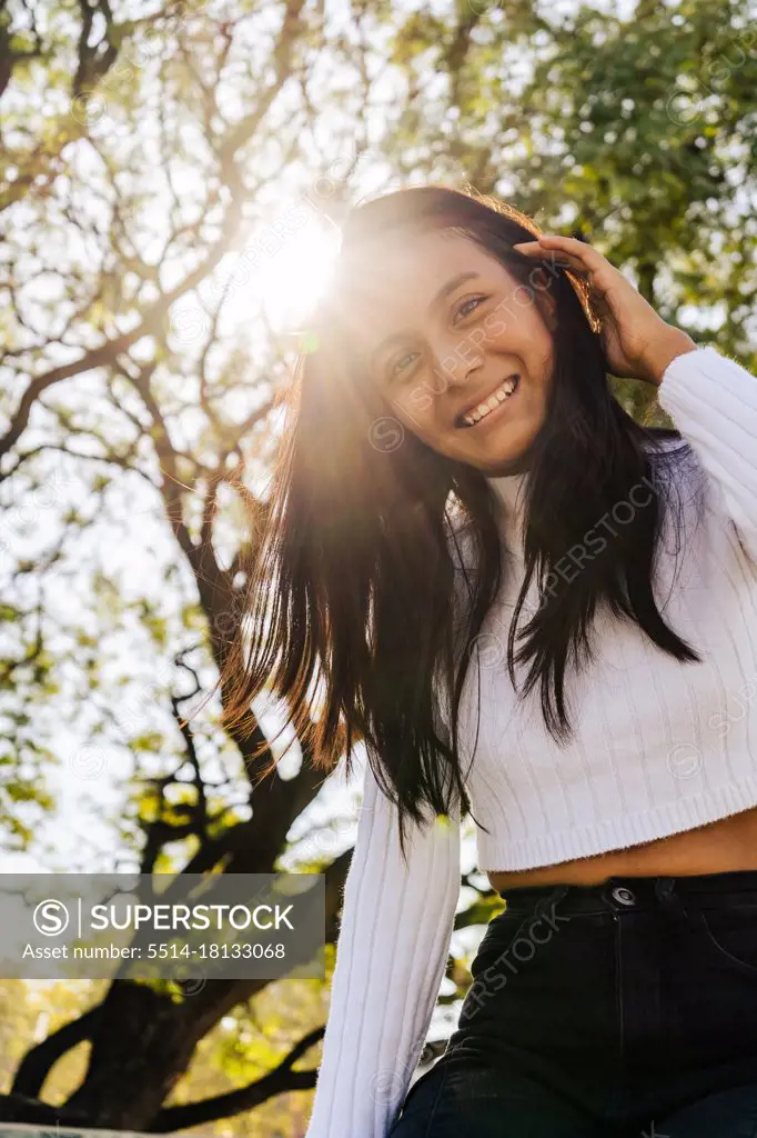 Smiling woman with autumn sunlight from behind.