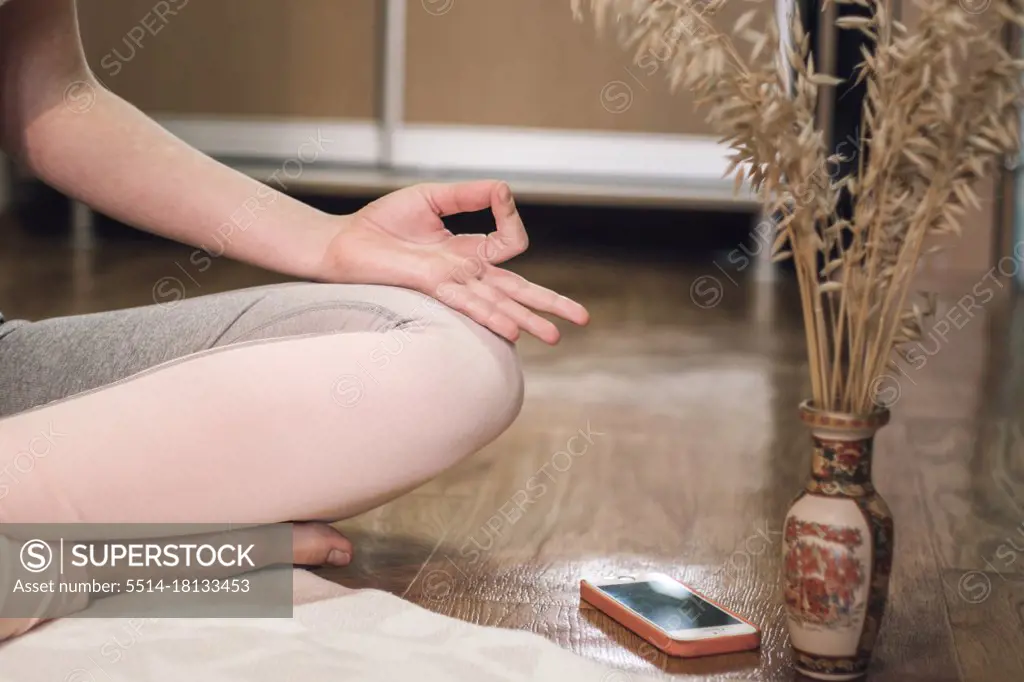 Low section of woman doing yoga in lotus position at home